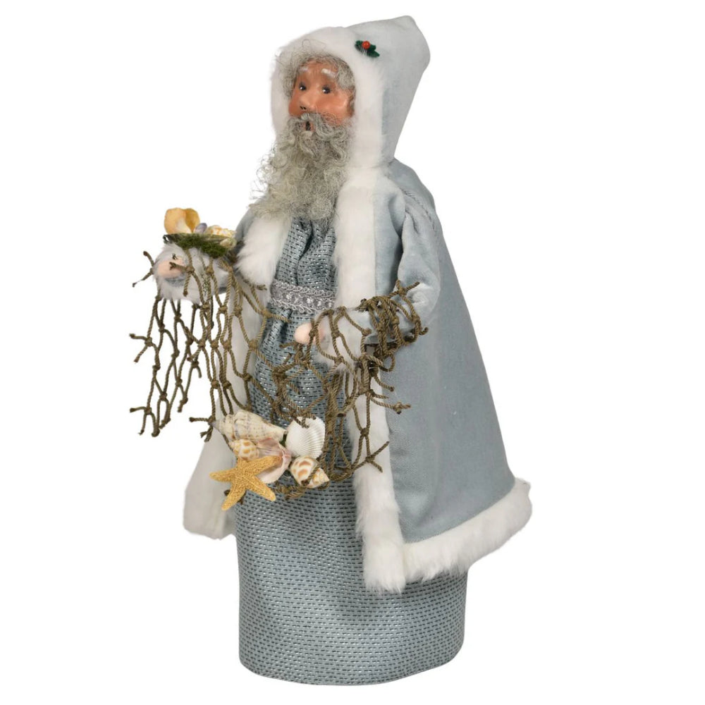 A right angled photo of the face of the decorative figure of the Nautical Santa in a gray outfit with white fur trim, holding starfish and seaweed on a white background.