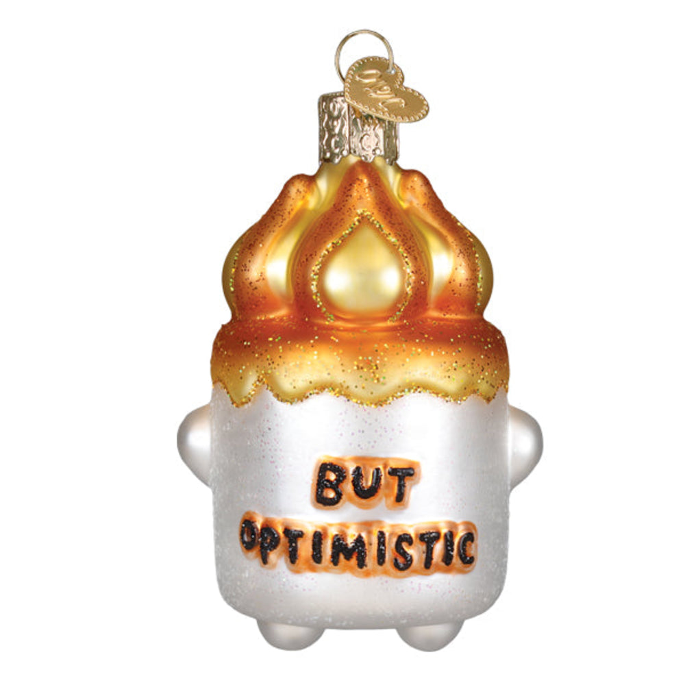 A novelty Christmas ornament shaped like a marshmallow with a flame on top, featuring the text 'BUT OPTIMISTIC' in black letters on an orange-brown background, on a plain white background.