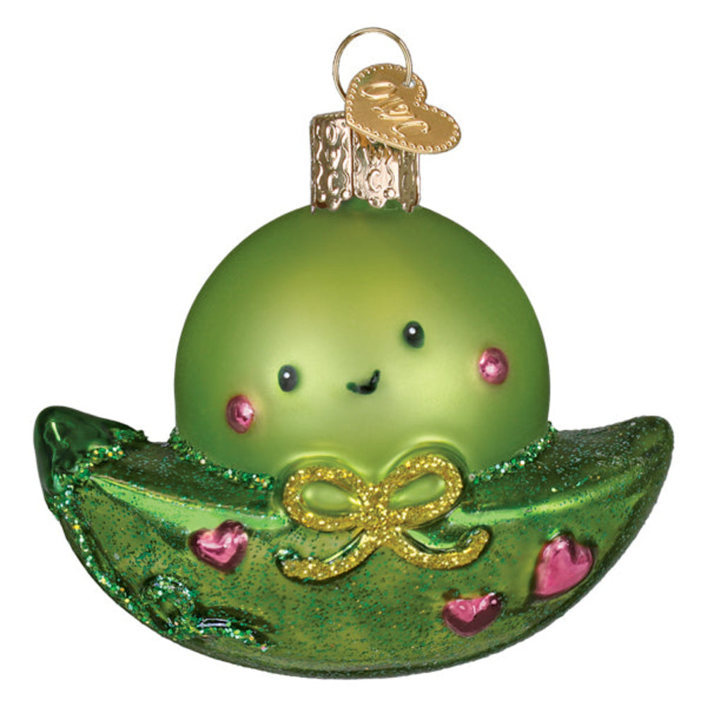 Green glass ornament shaped like a pea pod with a face on a white background