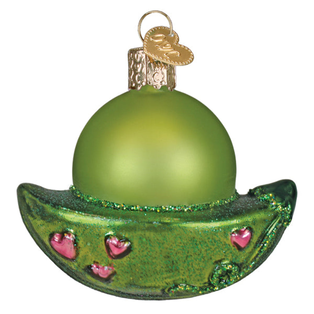 Green glass ornament shaped like a peapod with pink hearts on a white background