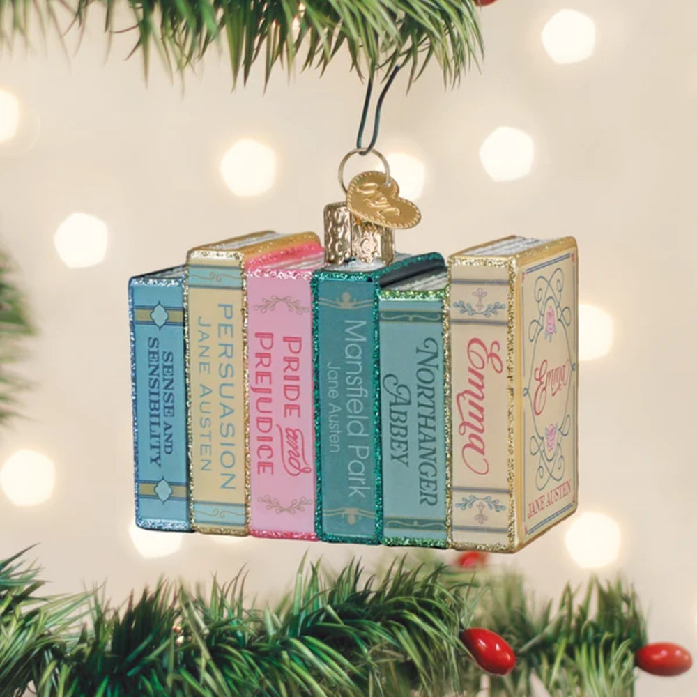 Ornament shaped like a stack of books on a Christmas tree with lights in the background