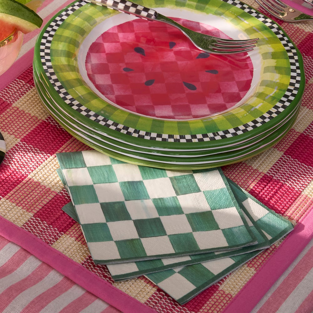 Stack of watermelon-themed paper plates with checkered napkins on a colorful tablecloth.
