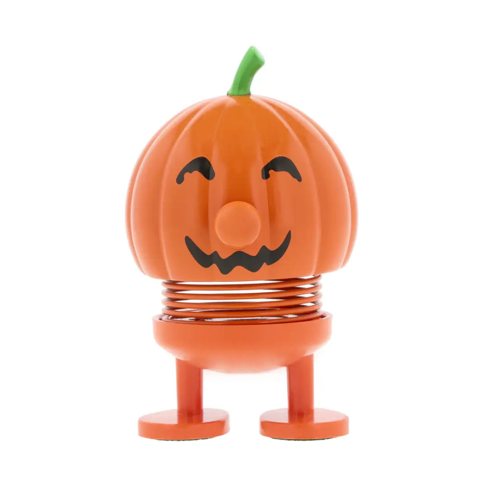 An orange pumpkin-shaped spring toy with a smiling jack-o'-lantern face, green stem, and small legs, photographed on a plain white background.