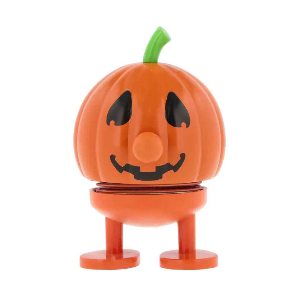 An orange jack-o'-lantern toy figure with a green stem, black facial features, and standing legs on a white background.