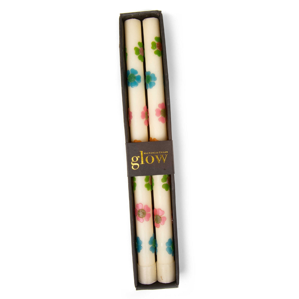 A set of two boxed white with muilt-colored floral-patterned candles with  on a white 