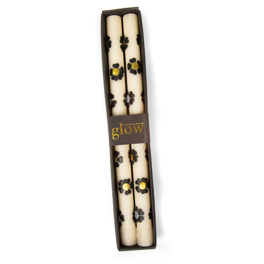 A set of two boxed white with silver & gold colored floral-patterned candles with on a white background