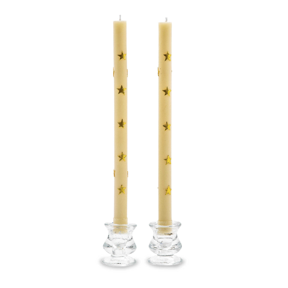 Two beige candles with gold star patterns in clear candle holders on a white background