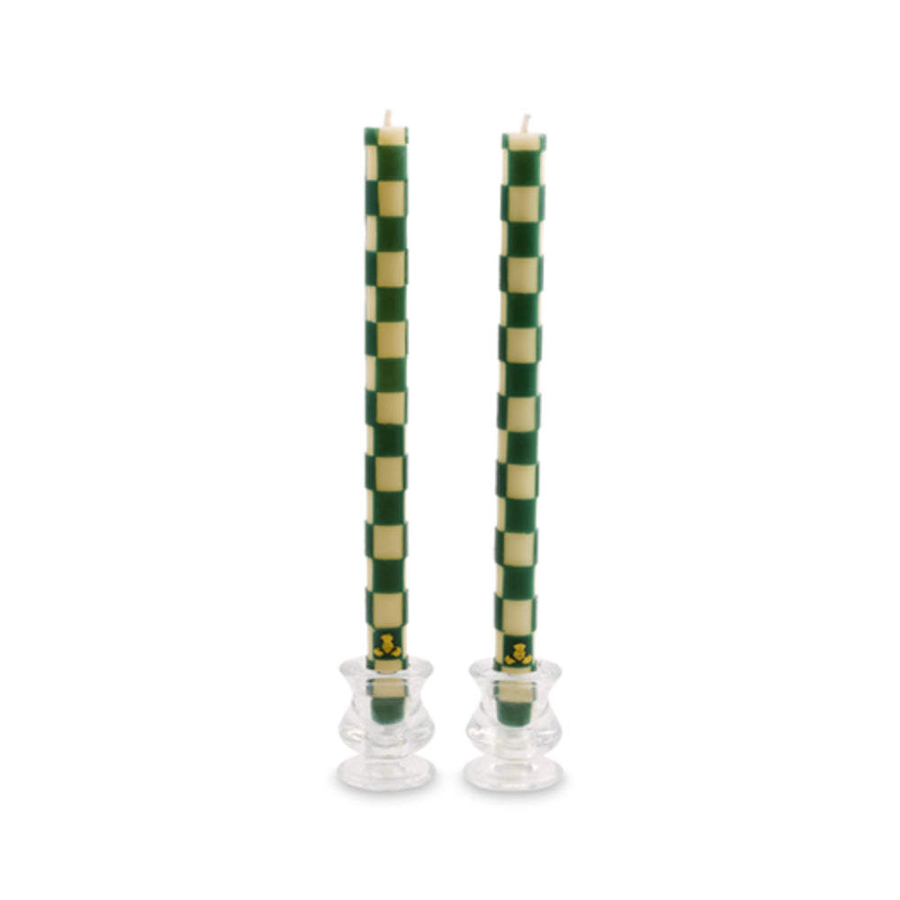 Two tall green and cream checkered taper candles in clear glass holders against a white background.