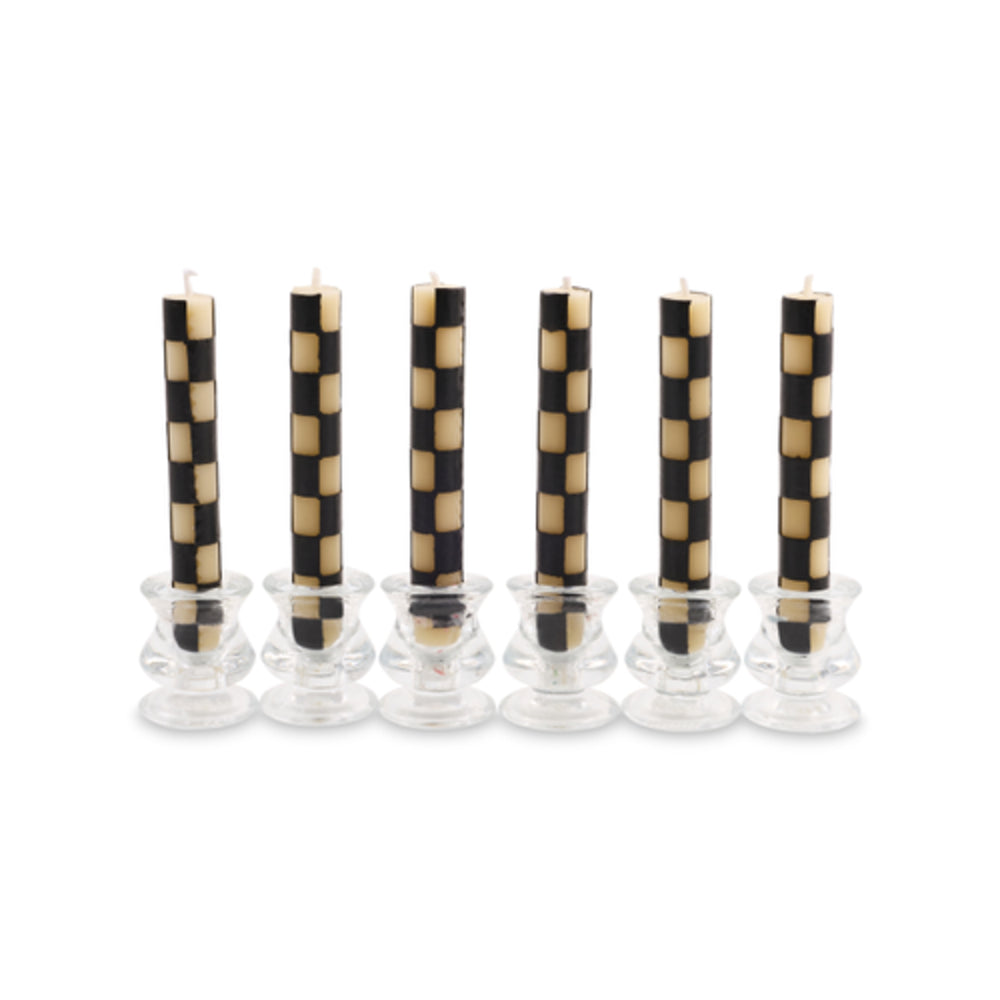 Six black and beige checkered taper candles standing in clear glass candle holders against a white background.