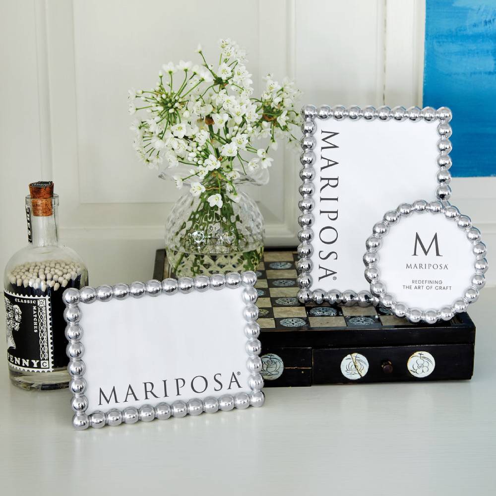 Mariposa picture frames on a surface with a bottle and flowers in the background