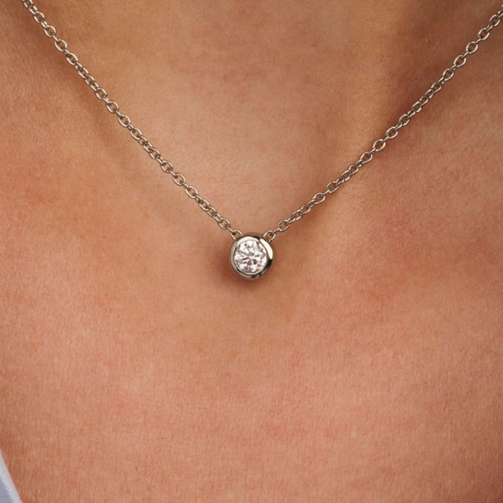 Silver necklace with a round pendant on a person's neck