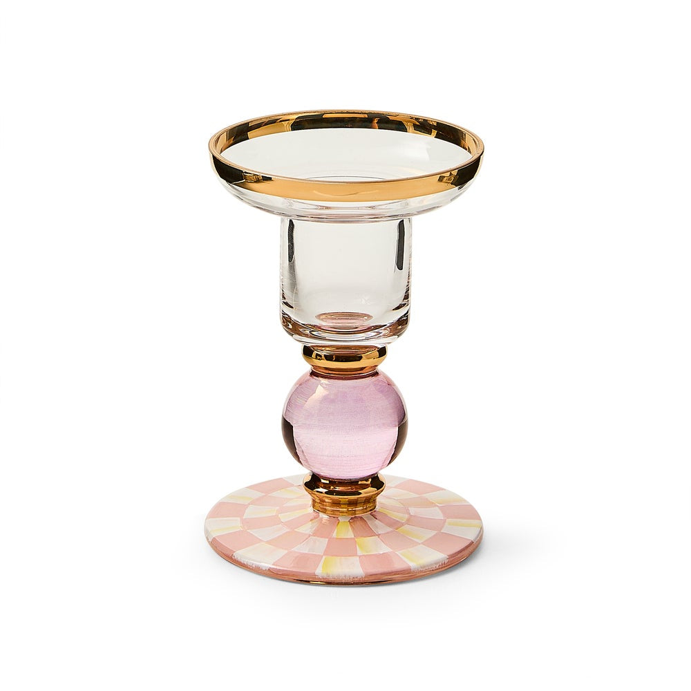 Decorative glass candle holder with gold rim and pink base on a white background