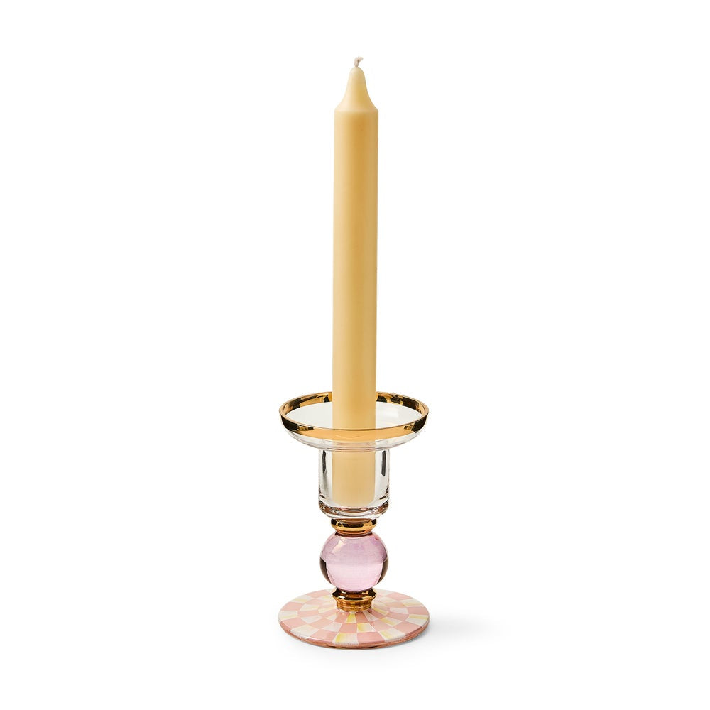 Candle holder with a pink base and gold rim holding a beige candle on a white background
