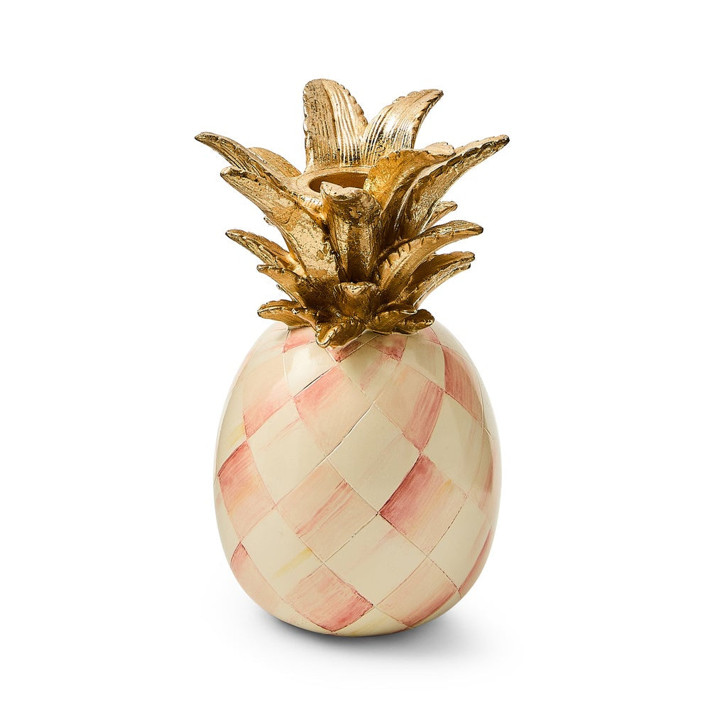 Decorative pineapple with gold top and pink and white checkered pattern on a white background