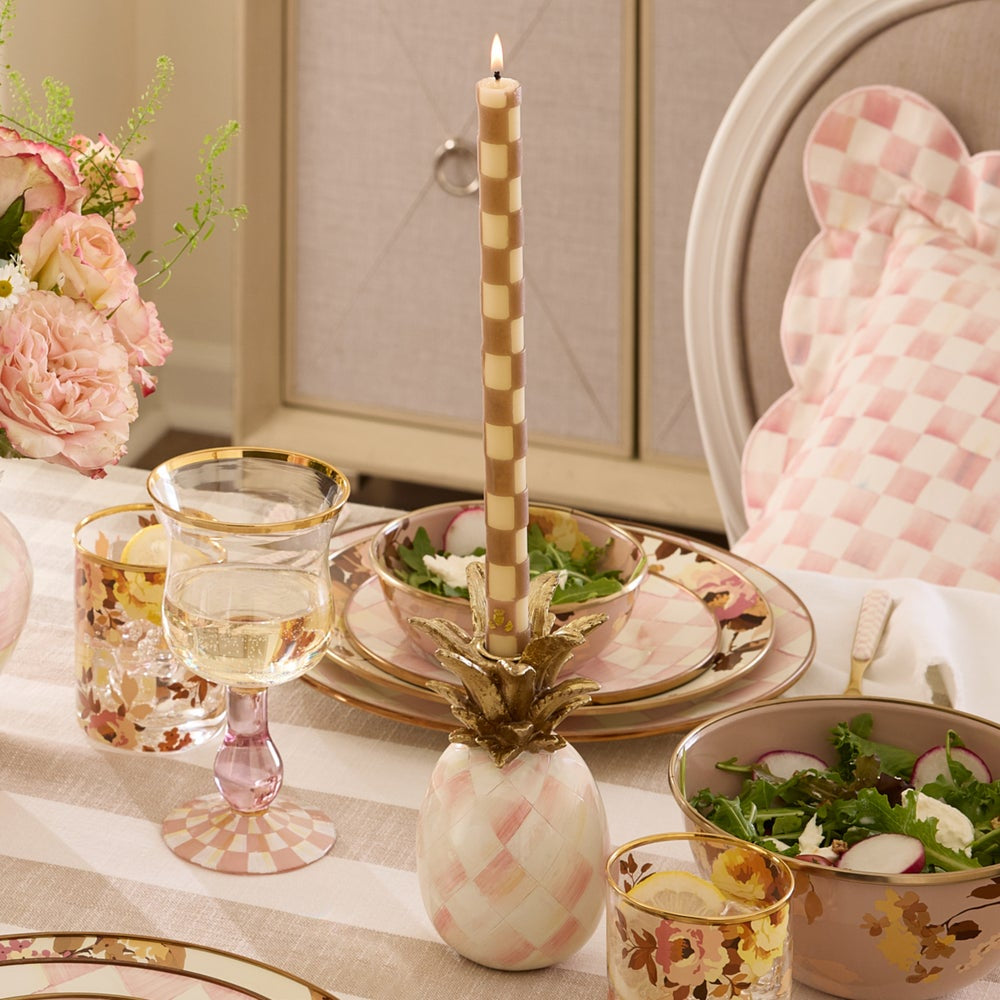 Decorative table setting with pineapple candle holder, glasses, and floral arrangements.
