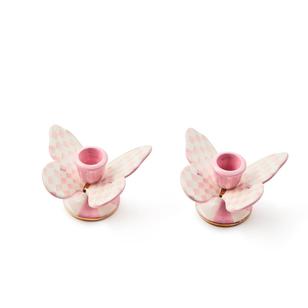 Two pink butterfly-shaped candle holders on a white background