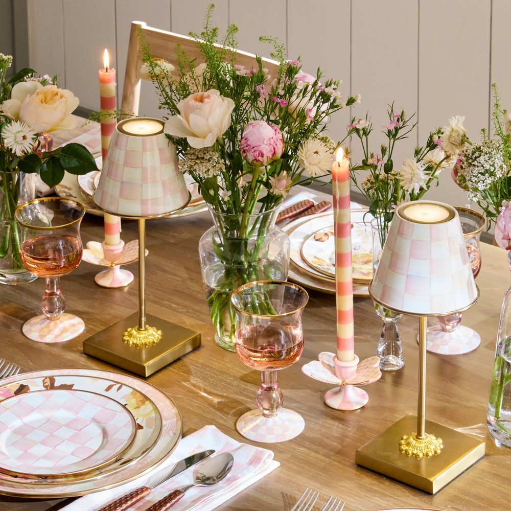 Dining table setting with floral arrangements, candles, and decorative lamps.