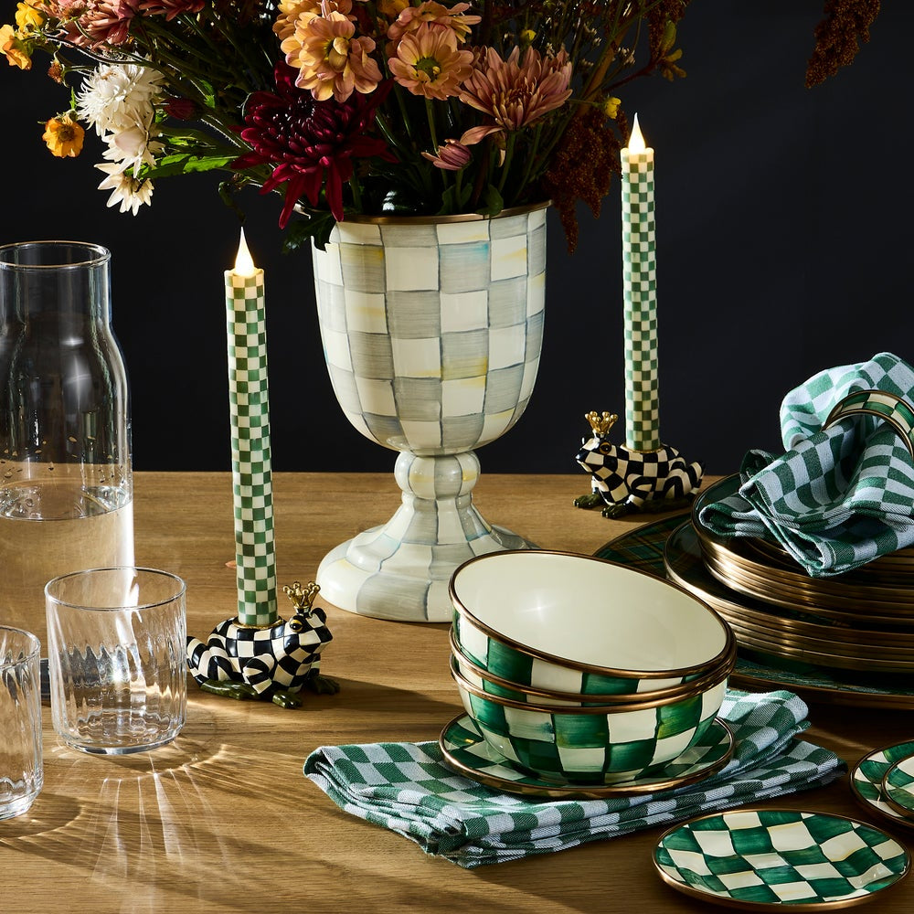 Decorative table setting with checkered patterns on tableware and candles.