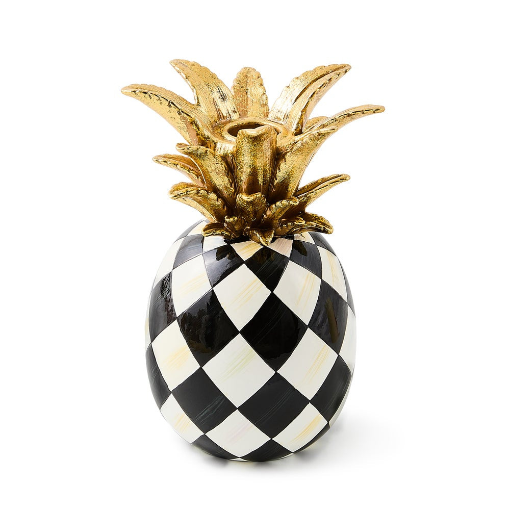 Decorative pineapple with gold top and black and white checkered pattern on a white background