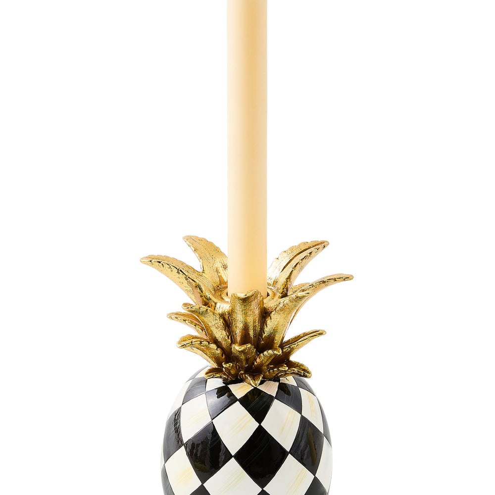 Decorative pineapple candle holder with gold top and black and white checkered base on a white background