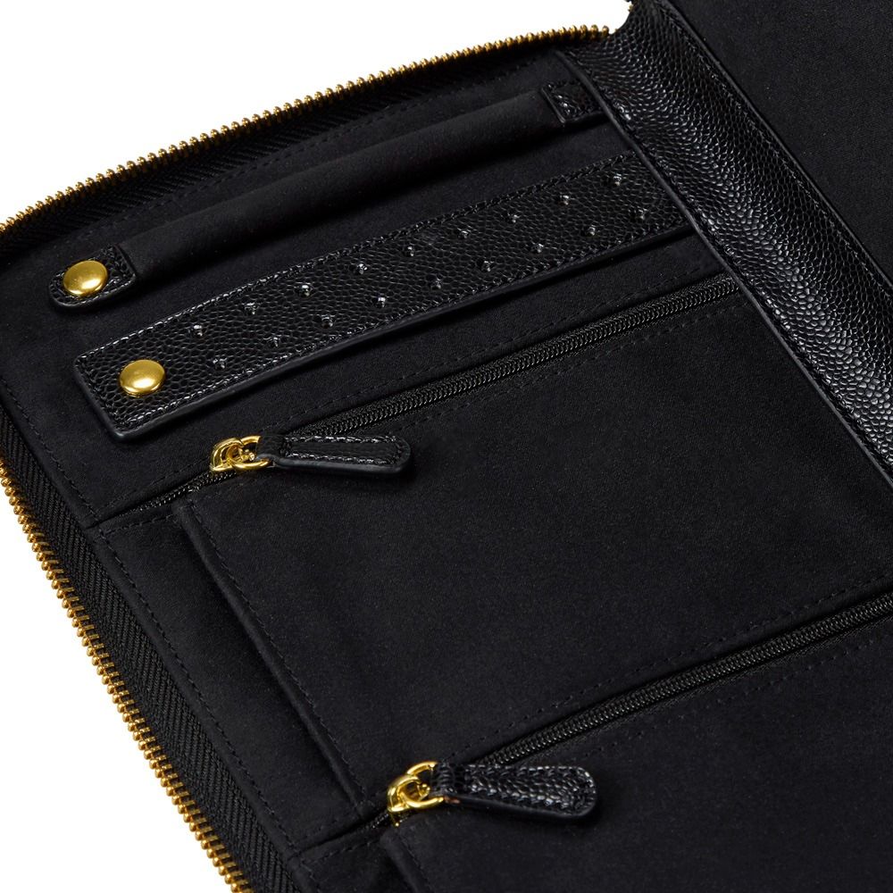 Close-up of a black leather and fabric zip-around wallet or organizer with gold-tone hardware, showing interior compartments, a textured strap, and zipper pulls on a white background.