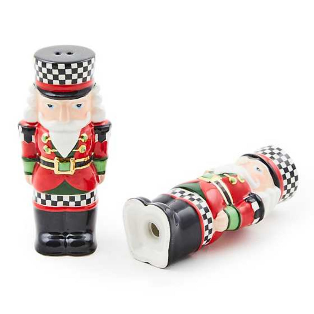 Two nutcracker-themed salt and pepper shakers with one on its side  on a white background