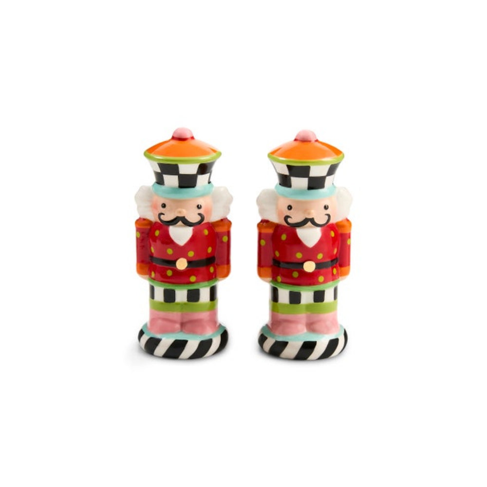 A pair of decorative nutcracker-shaped salt and pepper shakers with red and green striped bodies, white faces, and orange hats, set against a plain white background.