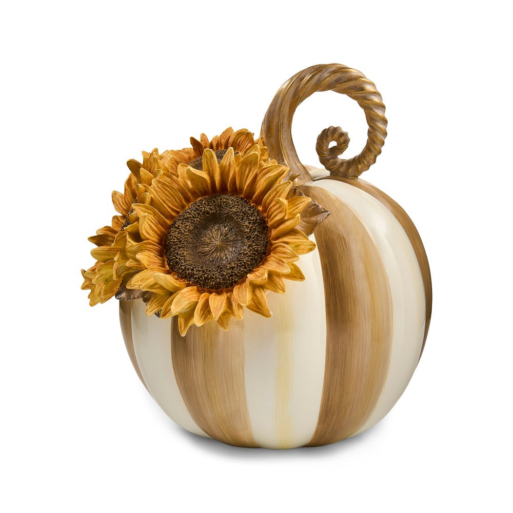 A decorative ceramic pumpkin with vertical tan and cream stripes, a twisted stem, and a large yellow sunflower attached near the top, shown on a plain white background.