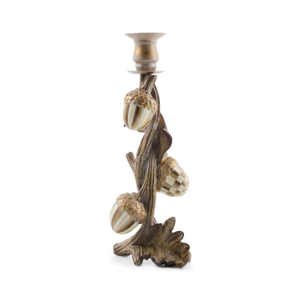 An ornate metal candlestick holder designed as a tree trunk with three acorns and leaves, featuring a brushed bronze finish with gold accents on the acorns and cup, set against a plain white background.