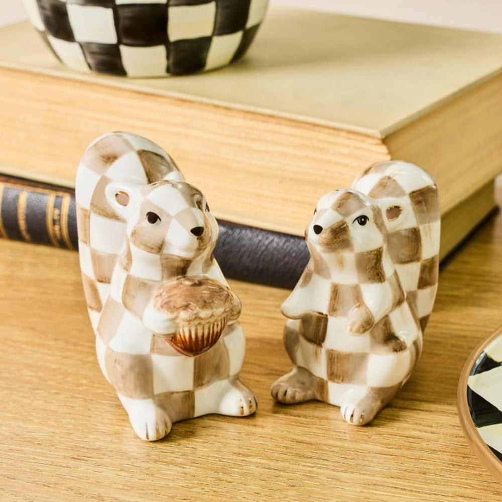 Two ceramic groundhog figurines with a brown and cream checkered pattern, displayed on a wooden surface with vintage books in the background.