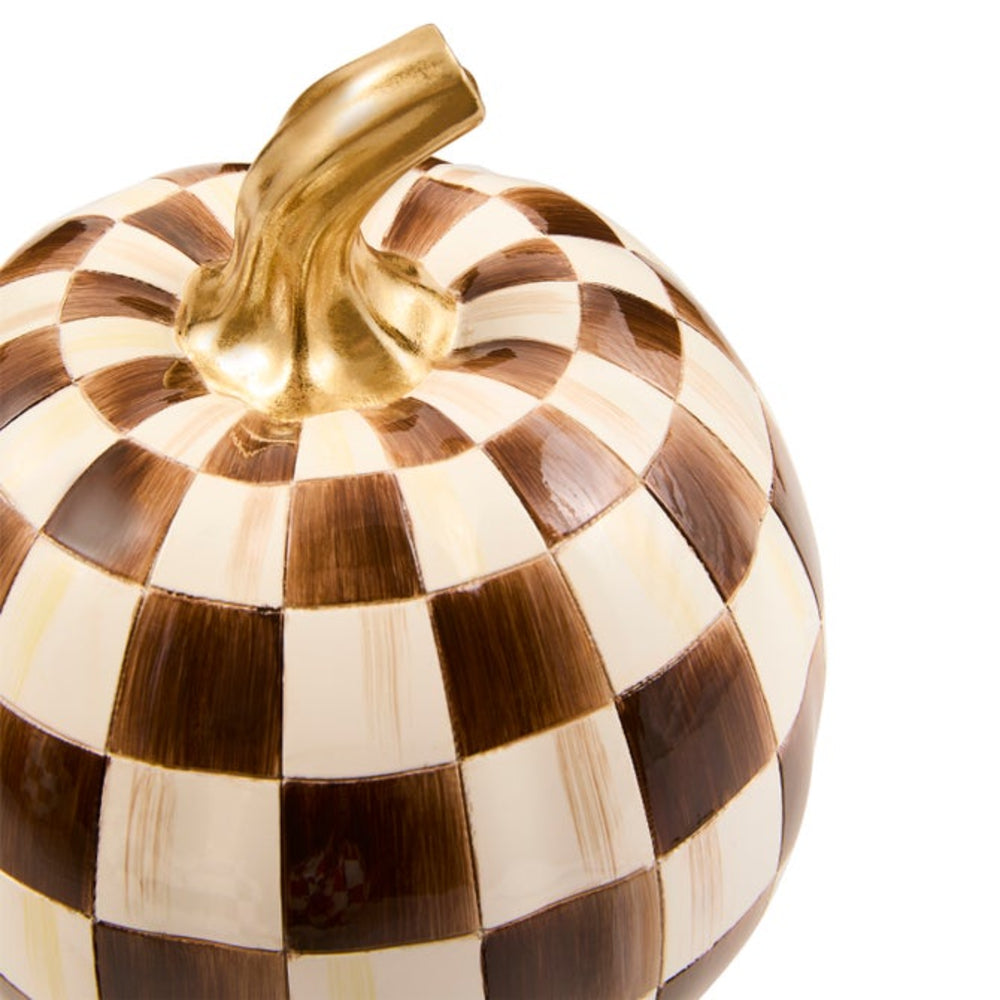 A decorative pumpkin with a brown and cream checkerboard pattern and a metallic gold stem, shown on a plain white background.