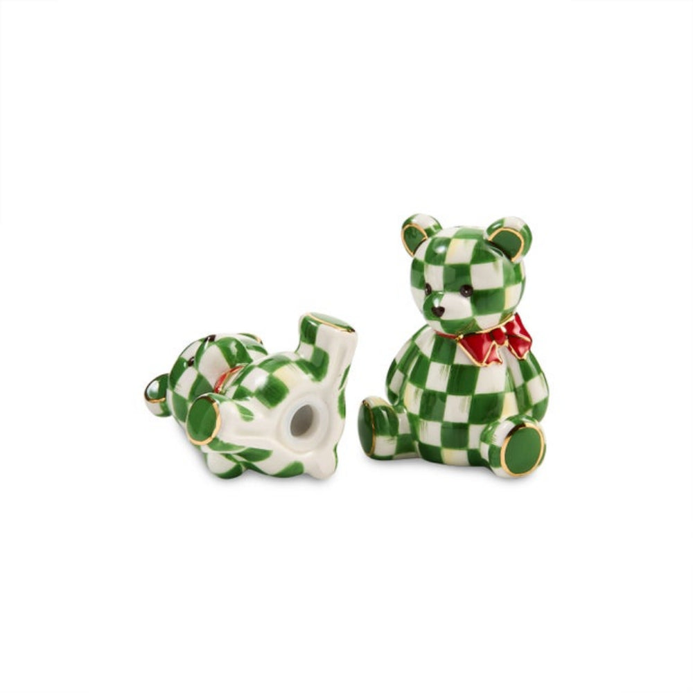 A pair of green and white checkered ceramic teddy bear salt and pepper shakers, one sitting upright with a red bow and one lying on its back, set against a plain white background.