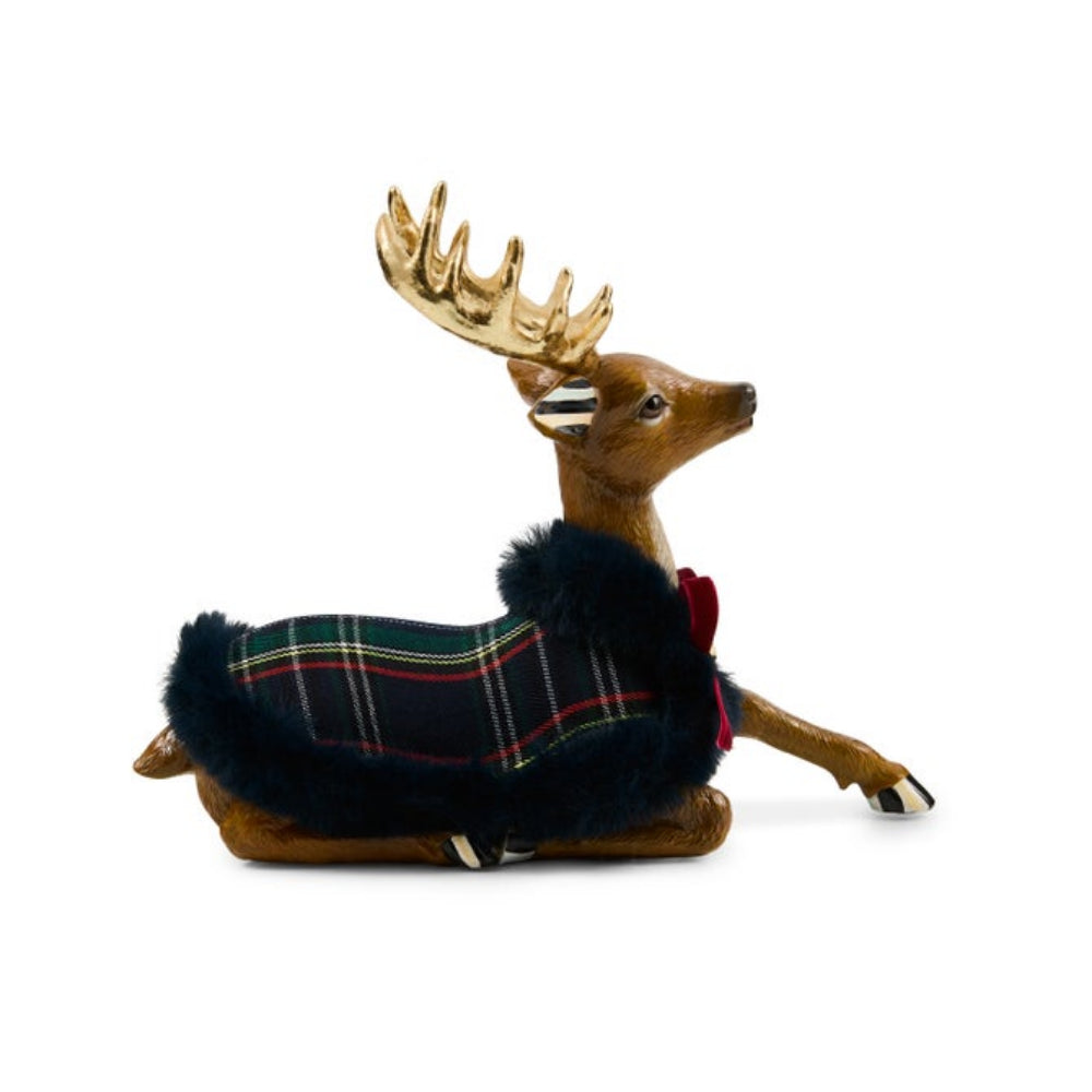 A decorative deer figurine wearing a dark navy tartan plaid coat with red and yellow stripes, a black faux-fur collar, and a small red bow, set against a plain white background.