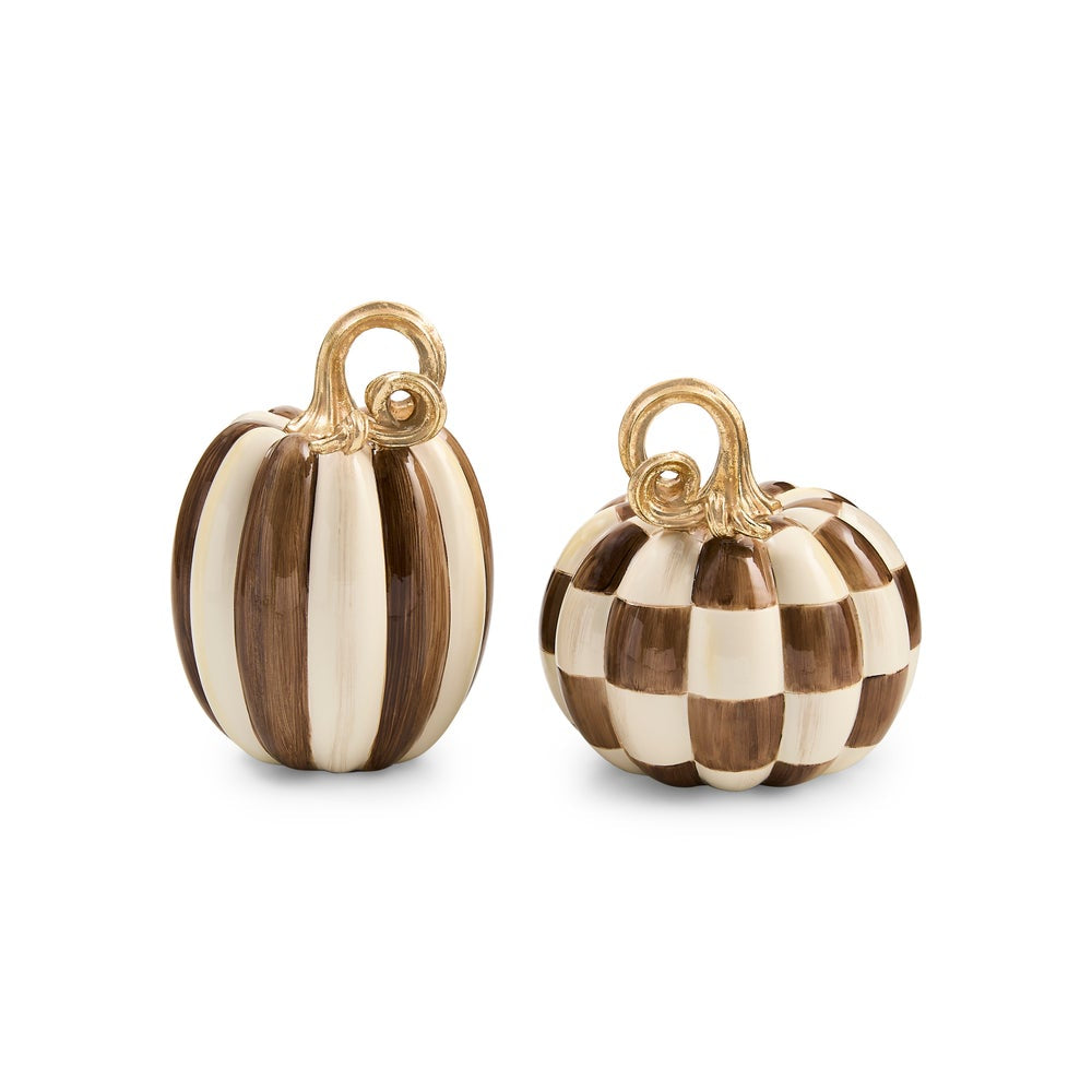 Two decorative pumpkin ornaments on a white background, one with vertical brown and cream stripes and one with a brown and cream checkerboard pattern, both with gold-tone hanging loops.