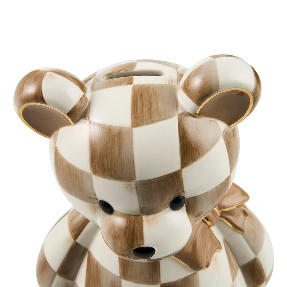A ceramic piggy bank shaped like a teddy bear, featuring a brown and cream checkered pattern with gold trim and a matching bow, shown against a plain white background.