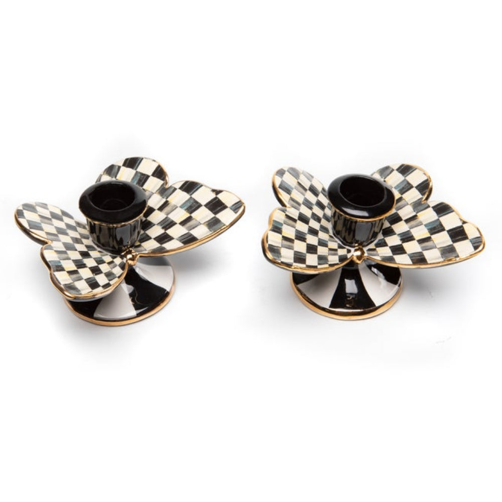 Two black and white checkered flower-shaped candle holders on a white background