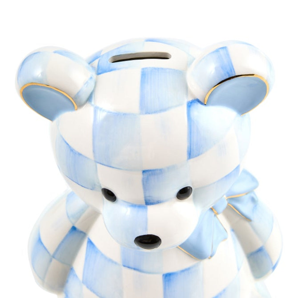 A ceramic piggy bank shaped like a teddy bear, decorated with a light blue and white checkered pattern and small gold trim, shown against a plain white background.