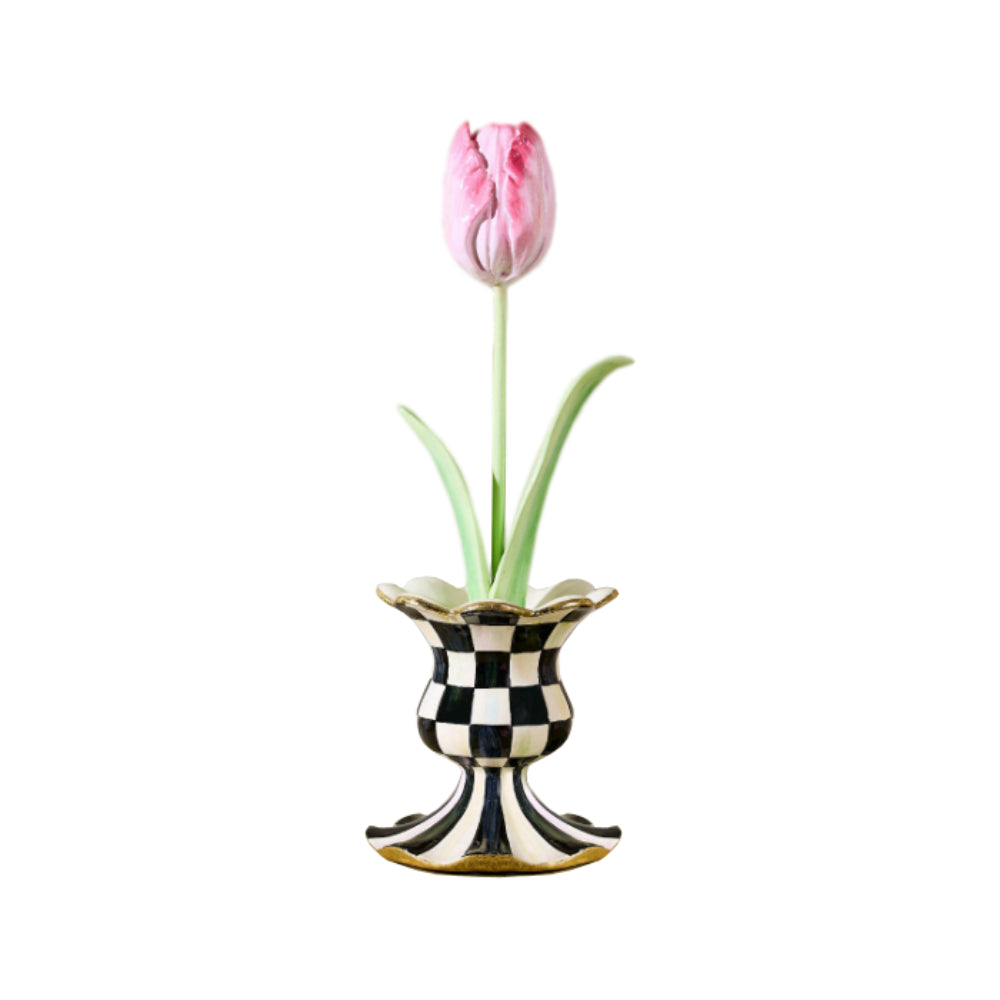 Pink tulip in a black and white checkered vase on a white background