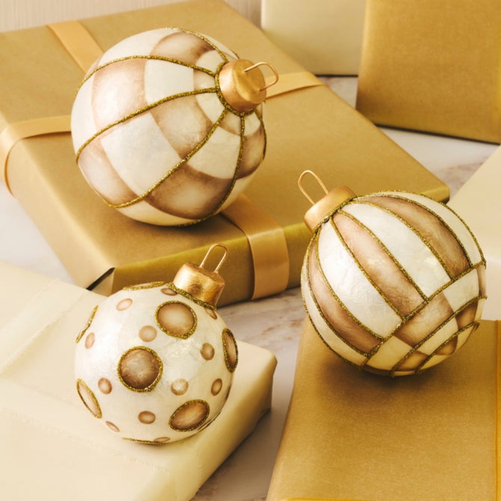 Three decorative Christmas ornaments in cream, beige, and white with gold accents with gold christmas gifts.