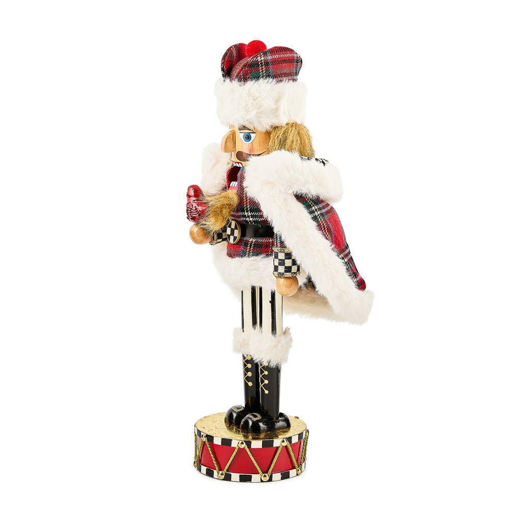 Nutcracker figurine in Scottish costume with tartan kilt and hat on a white background