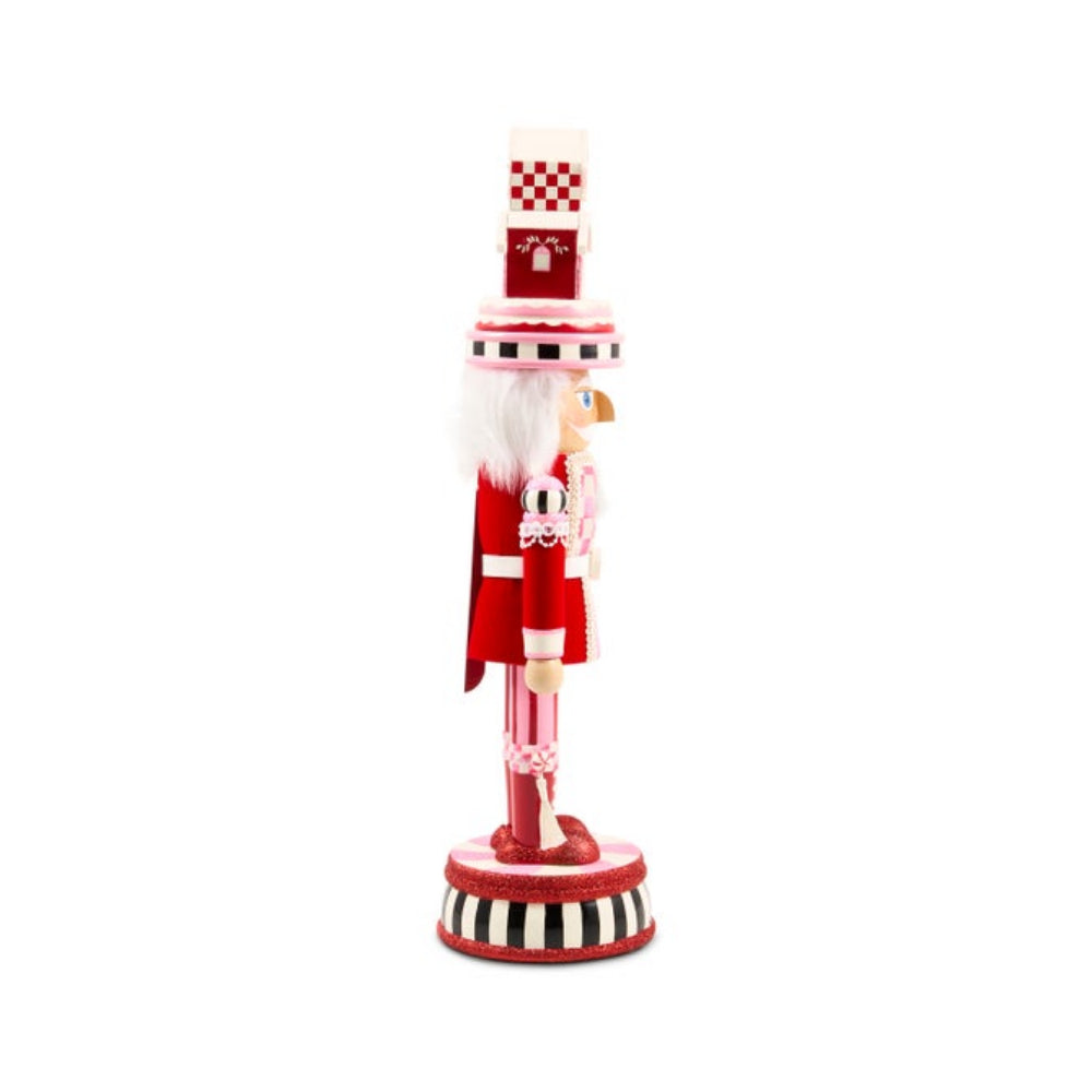 A red and white Christmas nutcracker figurine standing on a striped circular base against a plain white background.