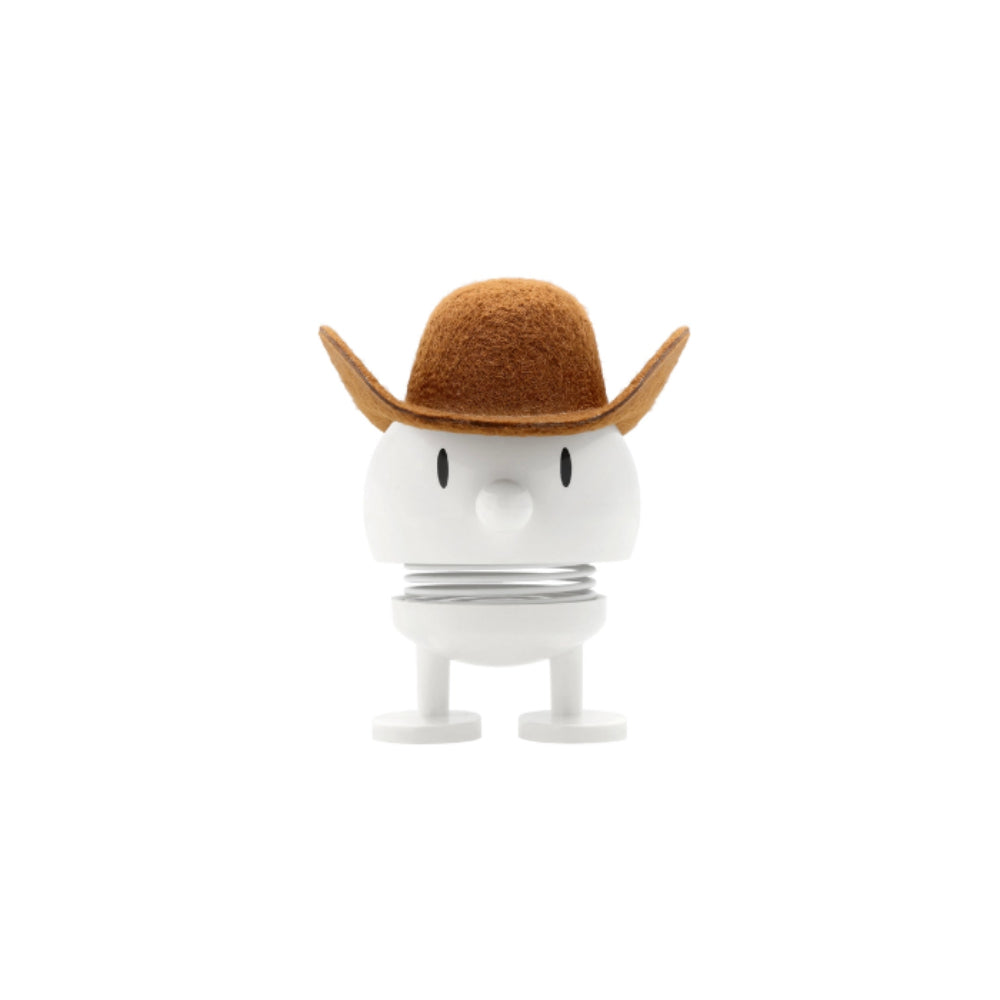 Small white figurine with a face and brown cowboy hat on a white background