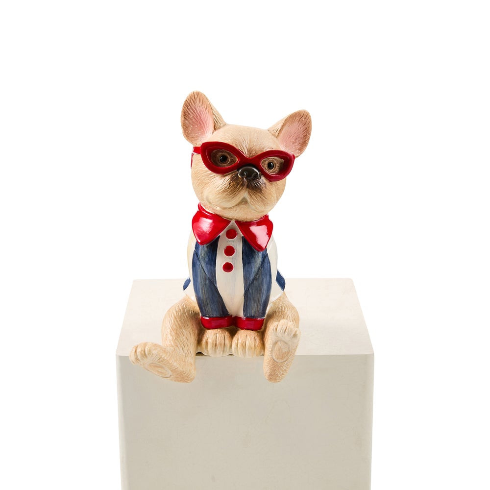 A small tan dog figurine wearing red glasses, a red bow tie, and a blue-and-white tuxedo, sitting on a white pedestal against a white background.
