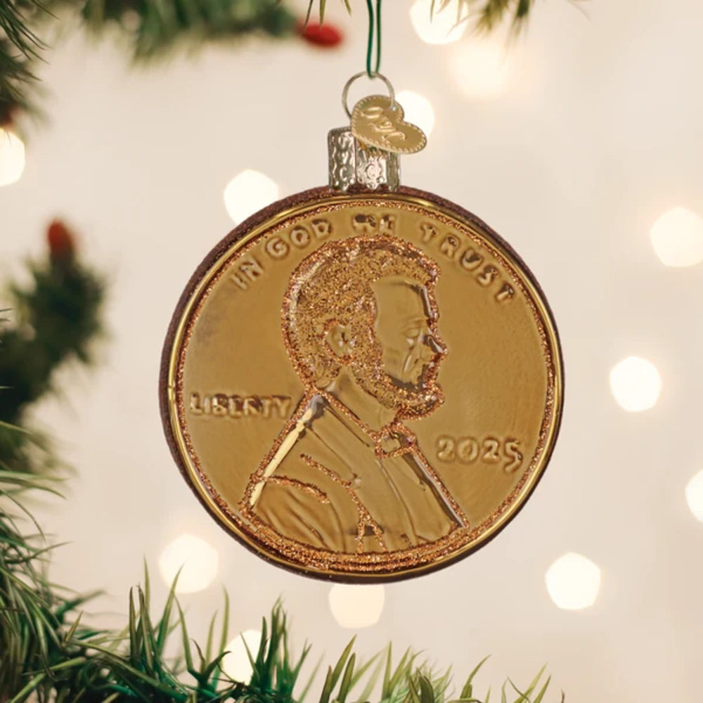 Gold coin ornament with 'In God We Trust' and 'Liberty' on a Christmas tree.