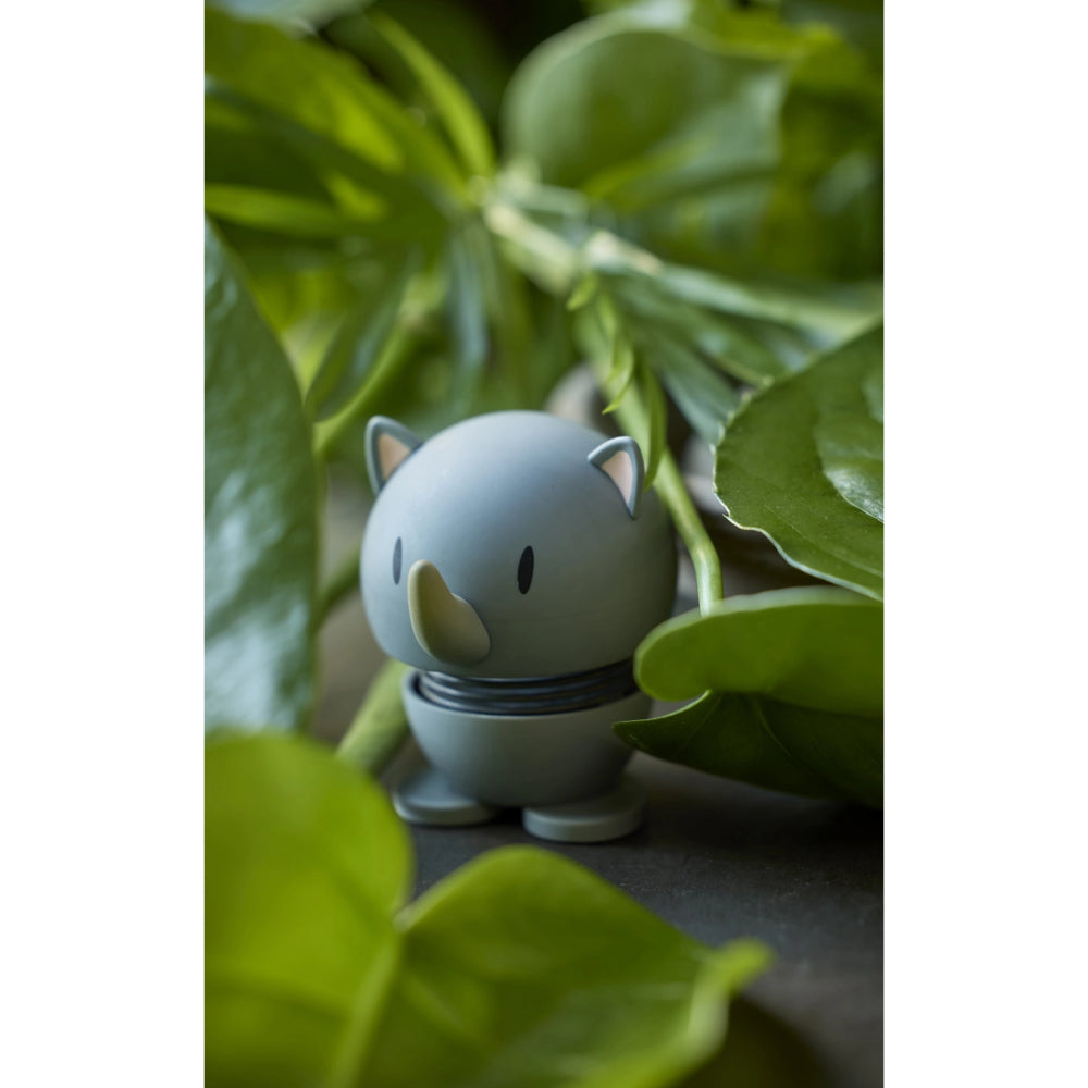 Grey rhino shaped figurine with a spring on a white green leaves around it 