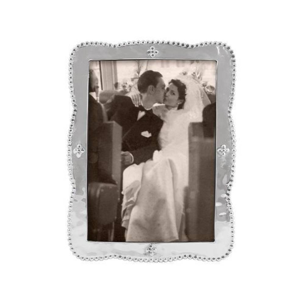 A silver-toned rectangular picture frame with a decorative beaded border and small corner embellishments, holding a black-and-white portrait photo of a newlywed couple