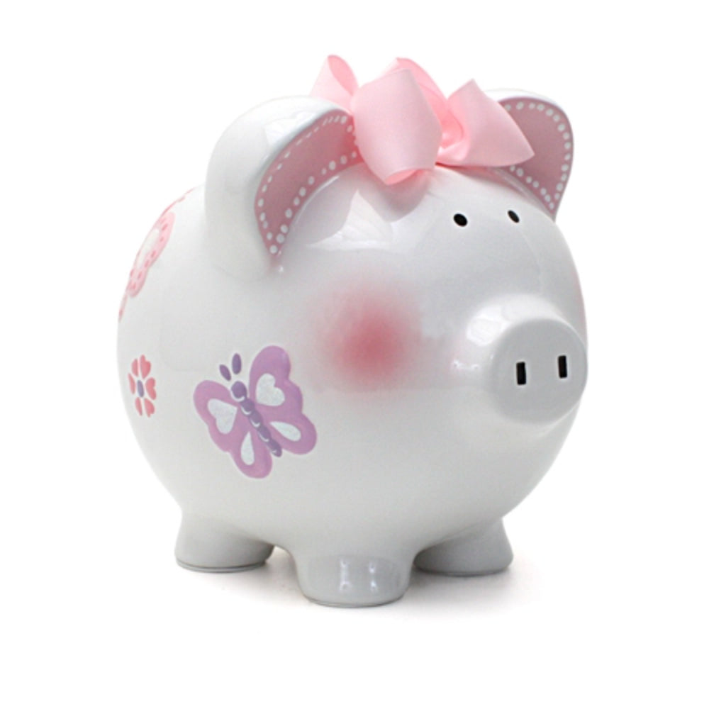 A white ceramic piggy bank with pink and purple butterfly decorations, pink ears, and a pink bow on top.