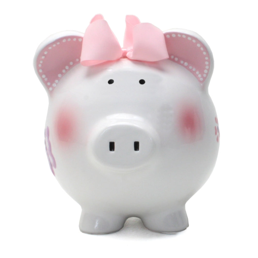 A white ceramic piggy bank with pink and purple butterfly decorations, pink ears, and a pink bow on top.