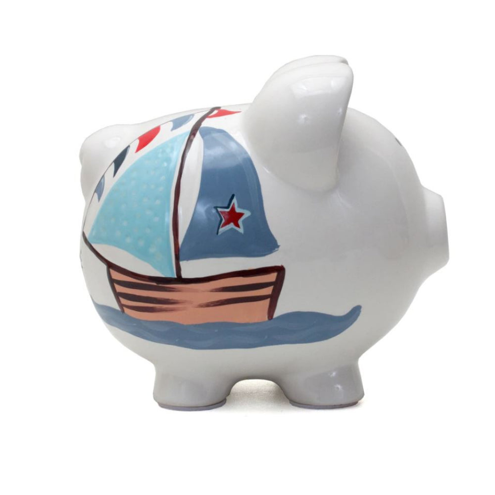 A side facing photo of a piggy bank with a sailboat design in blue and brown on a white background