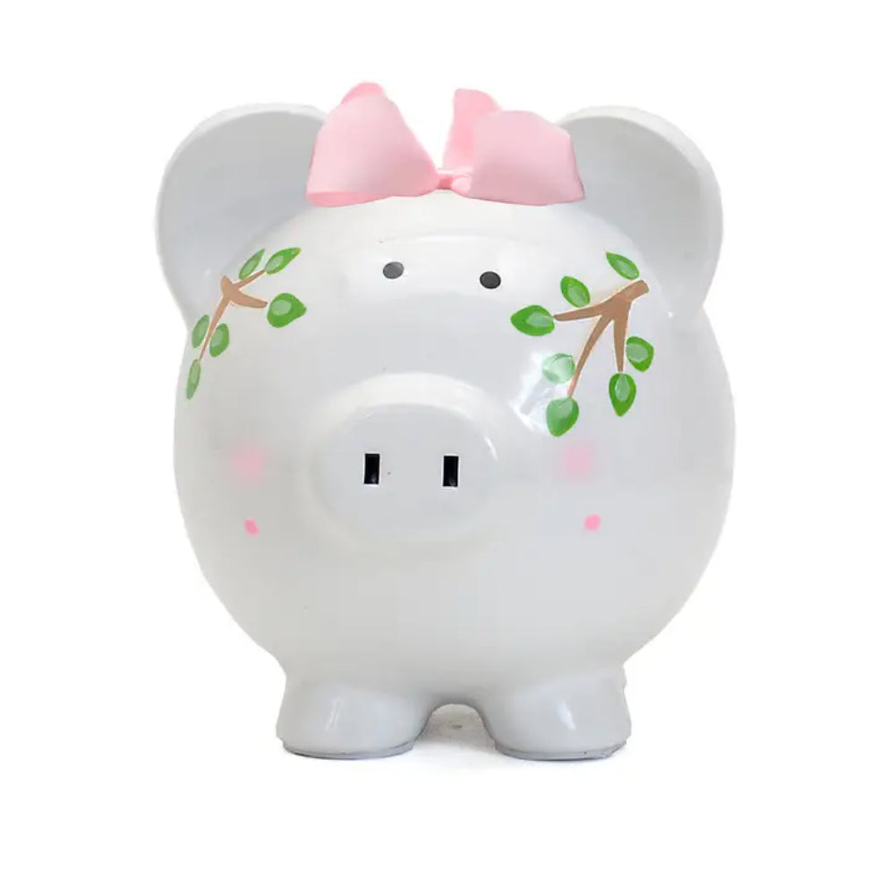 Front photo of a white piggy bank with a pink bow and green leaf design on a white background